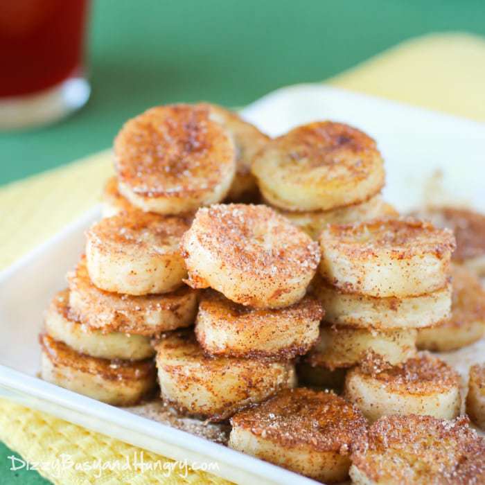 Front view of pan fried cinnamon bananas stacked in columns and rows on a white plate